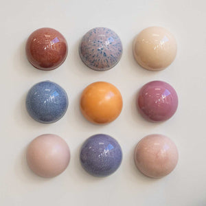 Nine colorful marble-like ceramic balls arranged in a 3x3 grid on a light background.