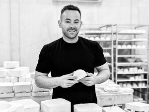 Sam Mayell Headshot in Queenstown Studio, holding slip-cast dome next to pottery moulds.